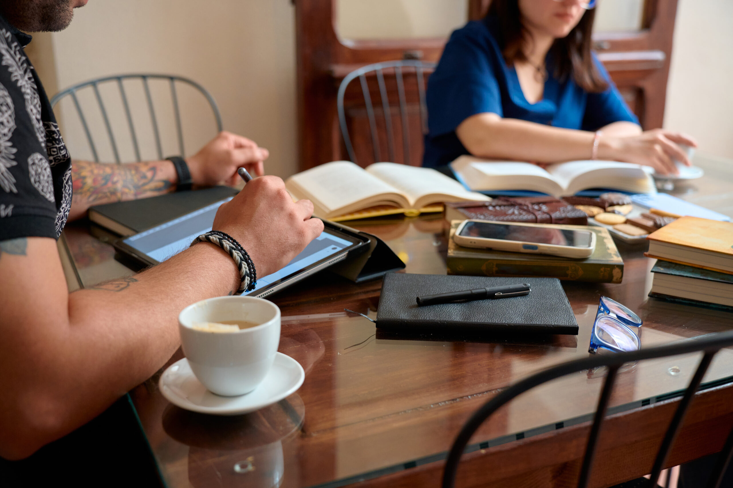 Students studying and drinking coffee at desk with books and tablet